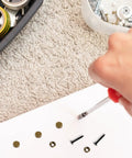 Hand using a screwdriver on Rock Solid Brass Decorative Screws With Caps For Furniture Cabinet And Mirror Install Self Tapping Wood Hardware Anti Rust Knockout Look Easy Diy Upgrade 12mm 8 Piece Set.