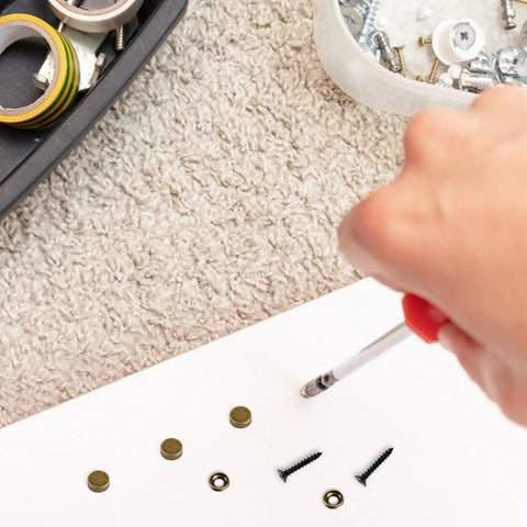 Hand using a screwdriver on Rock Solid Brass Decorative Screws With Caps For Furniture Cabinet And Mirror Install Self Tapping Wood Hardware Anti Rust Knockout Look Easy Diy Upgrade 12mm 8 Piece Set.