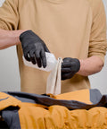 Person applying Aquaseal FD Flexible Durable Repair Adhesive to yellow and gray outdoor jacket, using black gloves, 0.75 oz