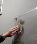VHB 4910F Clear Double-Sided Acrylic Adhesive Tape used for invisible bonding of a glass office sign, showcasing strong adhesion.