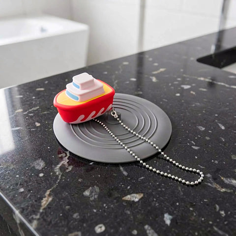 TEHAUX Silicone Bathtub Drain Stopper 6'', Hair Catcher for Bathroom on black countertop with playful boat design.