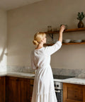 Woman reaching for an item on a wooden shelf supported by a Beefy 12 Inch by 8 Inch Heavy Duty Shelf Brackets 600 Lb Per Pair, in a kitchen.