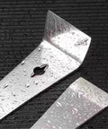 Close-up of shiny wet Beefy Stainless Steel Crowbars Set With Flat Head Pry Bars And Scrapers, dual ends shown on black surface.