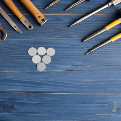10 Pack 1 Inch Stainless Steel Electrical Box Knockout Seal Plugs arranged on blue wooden surface with tools.