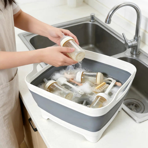 Collapsible Dish Basin With Drain Plug 2.4 Gal Foldable Sink For Kitchen RV Camping And Dorm, filled with baby bottles being washed.
