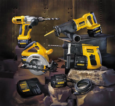Dewalt power tools set including drills, saw, and battery charger displayed on industrial background with bricks and metal pipes.