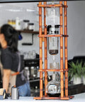 Retro Wood And Glass Cold Brew Tower Featuring Adjustable Stainless Steel Valve For Slow Ice Extraction Made For Crews Craving That Ultra Smooth Killer Cold Coffee Fix in cafe setting.