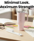 One Hand Tumbler Lid Opener With Ergonomic Lever next to a pink tumbler on a desk with glasses and stationery.