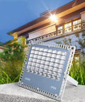 Heavy Duty 200W LED Flood Light With Tough As Nails Waterproof Housing For Yard Billboard And Deck Super Bright Outdoor Spot Lighting No Cap Badass Performance Rock Solid Build Hella Durable positioned in grassy area with modern building background.