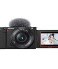 Front view of ZV-E10 Mirrorless Camera Kit With 16-50mm Lens, screen flipped, capturing a smiling person, ideal for vlogging.