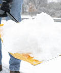 18 Inch Collapsible Poly Snow Shovel With Metal Wearstrip lifting snow, close-up of yellow blade with snow, man in jeans using shovel