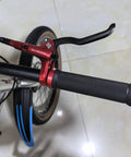 Fat-Cattie red hydraulic brake lever on bicycle handlebar with knurled black grip.