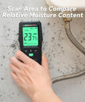Hand using Moisture Meter For Wood And Concrete With Digital Tester And Pinless Sensor Three Color LCD Display on a wall.