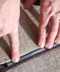 Hands installing Pre Caulking Filler Rope Backer Rod Roll Gray, 100 Foot Long, Quarter Inch Width into a concrete joint