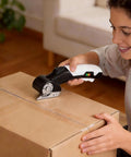 AyP Cordless Electric Scissors 4.2V Rotary Box Cutter With Utility Knife And Storage Case cutting a cardboard box.