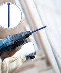 Worker using a drill with a 200 Piece Blue Hex Concrete Screw Anchors 1/4 X 3-1/4 Inch PTFE Carbon Steel bolt in masonry.