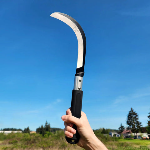 Hand holding K310 Brush Clearing Sickle With 9 Inch SK5 Japanese High Carbon Steel Blade And 9 Inch Aluminum Handle in clear sky.