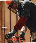 Heavy Duty Welding Arm Sleeves Featuring Flame Resistant Heat Burn Coverage And Flexible Elastic Fit Designed For Mechanics Welders And Tradesmen Demanding Badass Daily Protection, worn by a worker using a chainsaw.