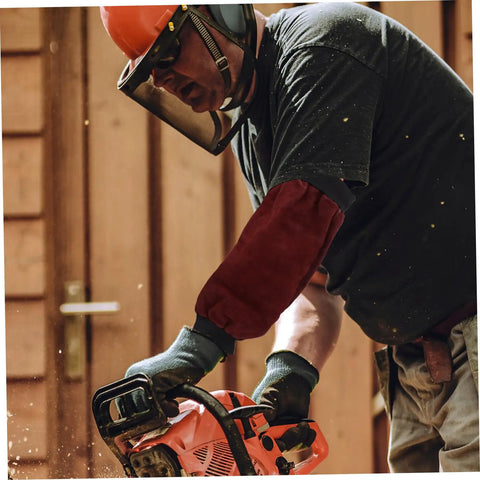 Heavy Duty Welding Arm Sleeves Featuring Flame Resistant Heat Burn Coverage And Flexible Elastic Fit Designed For Mechanics Welders And Tradesmen Demanding Badass Daily Protection, worn by a worker using a chainsaw.