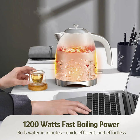 1.7L Electric Kettle With Stainless Steel Interior, BPA-Free, Cordless on desk next to hand holding cup, 1200W Fast Boil