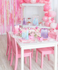 Pink party setup with Tie Dye Party Favor Bags With 36 Stickers 30 Pack, pink chairs, table, balloons, and decorations.