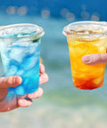 Two hands holding 16 Oz Clear Plastic Cups With Lids 50 Pack For Iced Coffee And Cold Drinks Strawless Sip Lids Perfect For Parties Outdoors