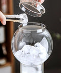 Premium Glass Cold Brew Drip Tower With Adjustable Flow Dripper For Smooth Cold Extraction Coffee Maker 600 Milliliter Gray Body adding ice cubes.