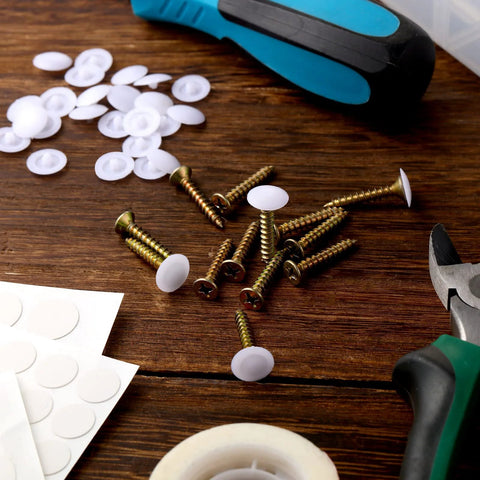 Plastic Self Tapping and Self Adhesive Screw Hole Covers for Wood Furniture, screws, covers, and tools on a wooden surface