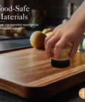 Hand using Oil Applicator Brush For Cutting Boards And Wooden Utensils on bamboo board, silver-ion sponge visible