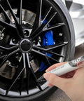 Hand using Professional Rim Paint Pen For Cars, Auto Touch Up Kit For Quick Scratch Repair on black alloy wheel.