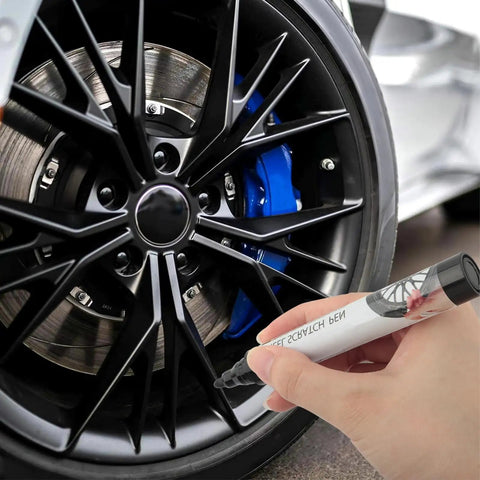 Hand using Professional Rim Paint Pen For Cars, Auto Touch Up Kit For Quick Scratch Repair on black alloy wheel.