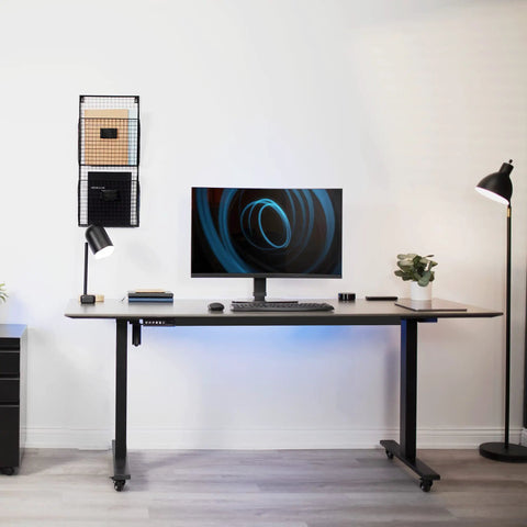 Durable Heavy Duty Freestanding Monitor Mount Desk Stand Rock Solid Height Adjustable Arm For 17 To 32 Inch Screens on a desk with lamp and plant.