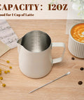 12 Oz Milk Frothing Pitcher With Clear Scale 304 Stainless Steel Barista Pouring Cup For Latte Art Cappuccino And Espresso Pro Grade Home Coffee Accessory For Perfect Foam Durable And Easy To Clean White, on a coffee table with latte art and flowers.