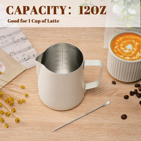 12 Oz Milk Frothing Pitcher With Clear Scale 304 Stainless Steel Barista Pouring Cup For Latte Art Cappuccino And Espresso Pro Grade Home Coffee Accessory For Perfect Foam Durable And Easy To Clean White, on a coffee table with latte art and flowers.