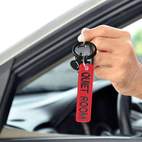 Person holding Personalized Embroidered Keychain With Double Sided Name Text. Red keychain close-up view with car key.