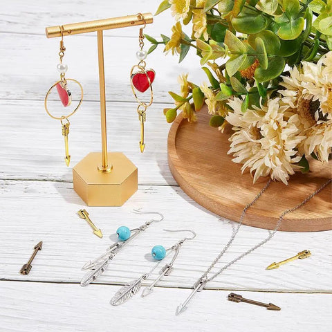 Arrowhead Charms 60Pcs Set In Gold Silver Bronze Three Colors Tibetan Style Alloy Double Sided Miniature Charms For Jewelry Making And DIY Crafts Necklace Earrings Keychain displayed on a table.