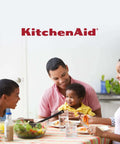 Happy family enjoying meal at dining table with KitchenAid branding.