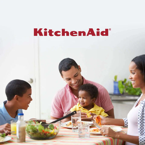 Happy family enjoying meal at dining table with KitchenAid branding.