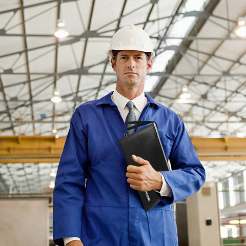 Engineer in blue uniform holding document bag on construction site. Visible: Two Size Fireproof Waterproof Document Bag Set 13.4x9.8 And 10.6x6.7 With Reflective Strip Zippers For A4 Files, Cash, Passport, Jewelry, Photos, And Important Docs, Heavy Duty Safe Storage Organizer Pouch.