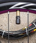 4 Piece Heavy Duty Aluminum Tire Valve Stem Caps For Tesla Cybertruck 2024 To 2026 on a bike tire with gold and black details.