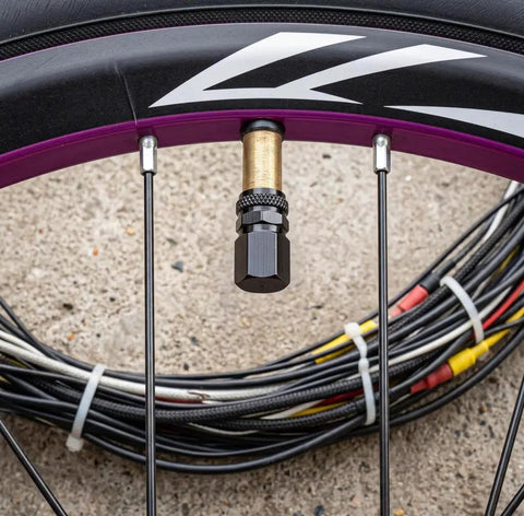 4 Piece Heavy Duty Aluminum Tire Valve Stem Caps For Tesla Cybertruck 2024 To 2026 on a bike tire with gold and black details.