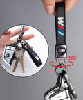 Hand holding BMW M Keyring And 4 Pack Dope Valve Stem Caps Car Keychain Set, showing black leather strap and 360-degree swivel.