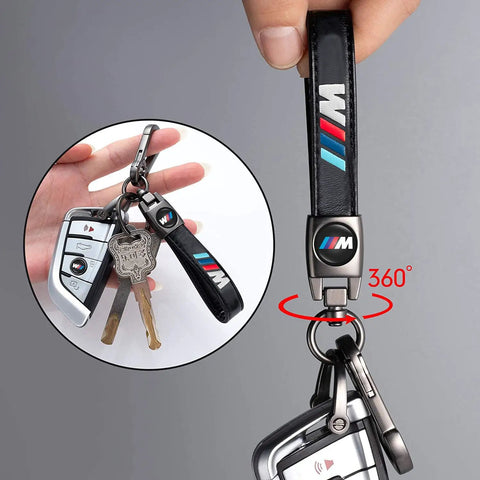 Hand holding BMW M Keyring And 4 Pack Dope Valve Stem Caps Car Keychain Set, showing black leather strap and 360-degree swivel.