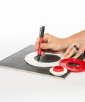 Person using Tile Drilling Template And Guide With Four Interlocking Rings For Precise Tile Holes on a black tile surface