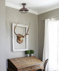 Straight Up Rustic Charm All Metal Barn Style Semi Flush Mount Ceiling Light Featuring Vintage Wire Cage Rust Finish ETL Certified above a wooden desk.