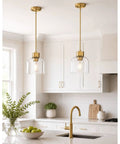 2 Pack 7 Inch Brushed Gold Pendant Lights With Crystal Clear Glass Shades For Kitchen Island And Dining Room above a modern kitchen sink.