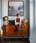 Child sitting on a wooden cabinet with Ten Pack 3 Inch Flat Black Drawer Pulls Cup Cabinet Handles For Kitchen Cabinets And Furniture.
