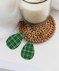 Totally Fire Green Grid Teardrop Faux Leather Dangle Earrings With Silver Plated Hooks resting on a woven coaster.