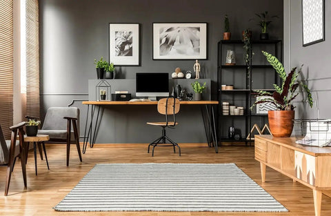 Modern home office with wood furniture, plants, and framed pictures on gray walls with heavy duty picture hangers kit for wood frames.