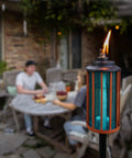 Retro Stripe Glass Torches 2 Pack 65 Inch Outdoor Patio Garden Torches Easy Install With Refillable Canisters Long Lasting Wicks Snuffer Blue And Copper shown lit on patio